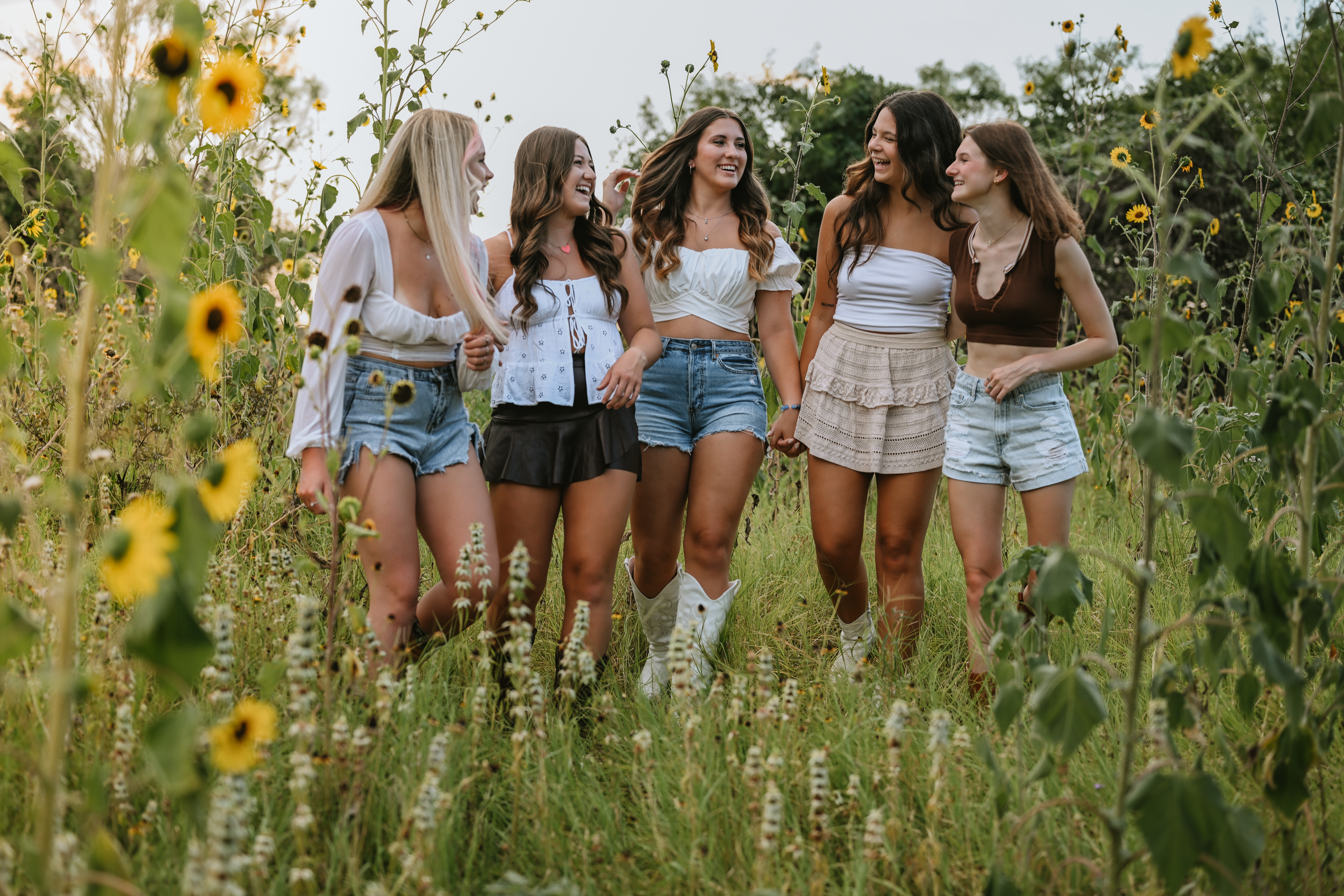 group of girl friends walking through a field of tall grass and sunflowers in west Austin at commons ford metro park