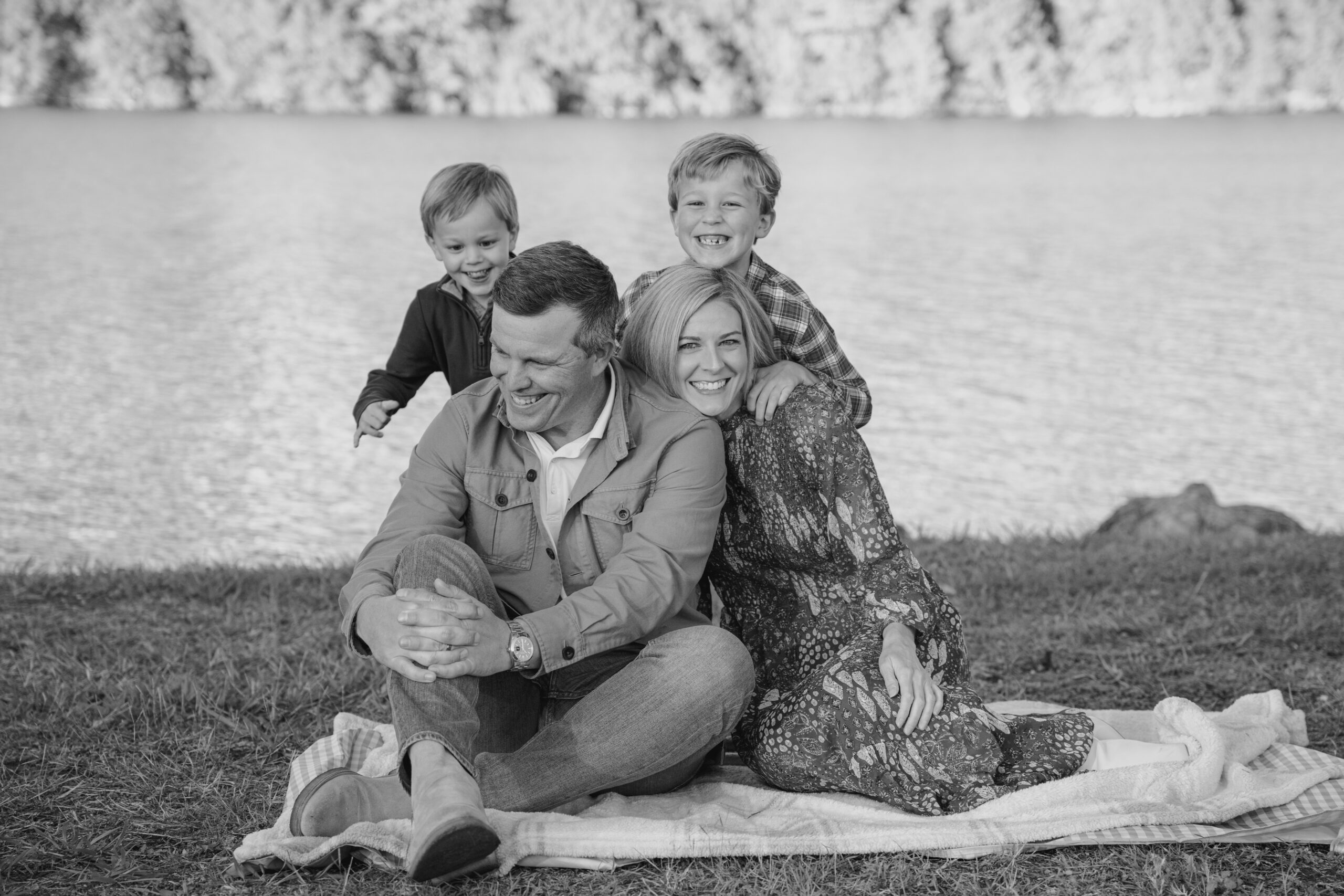 family of four laughing together in a field by lake Austin