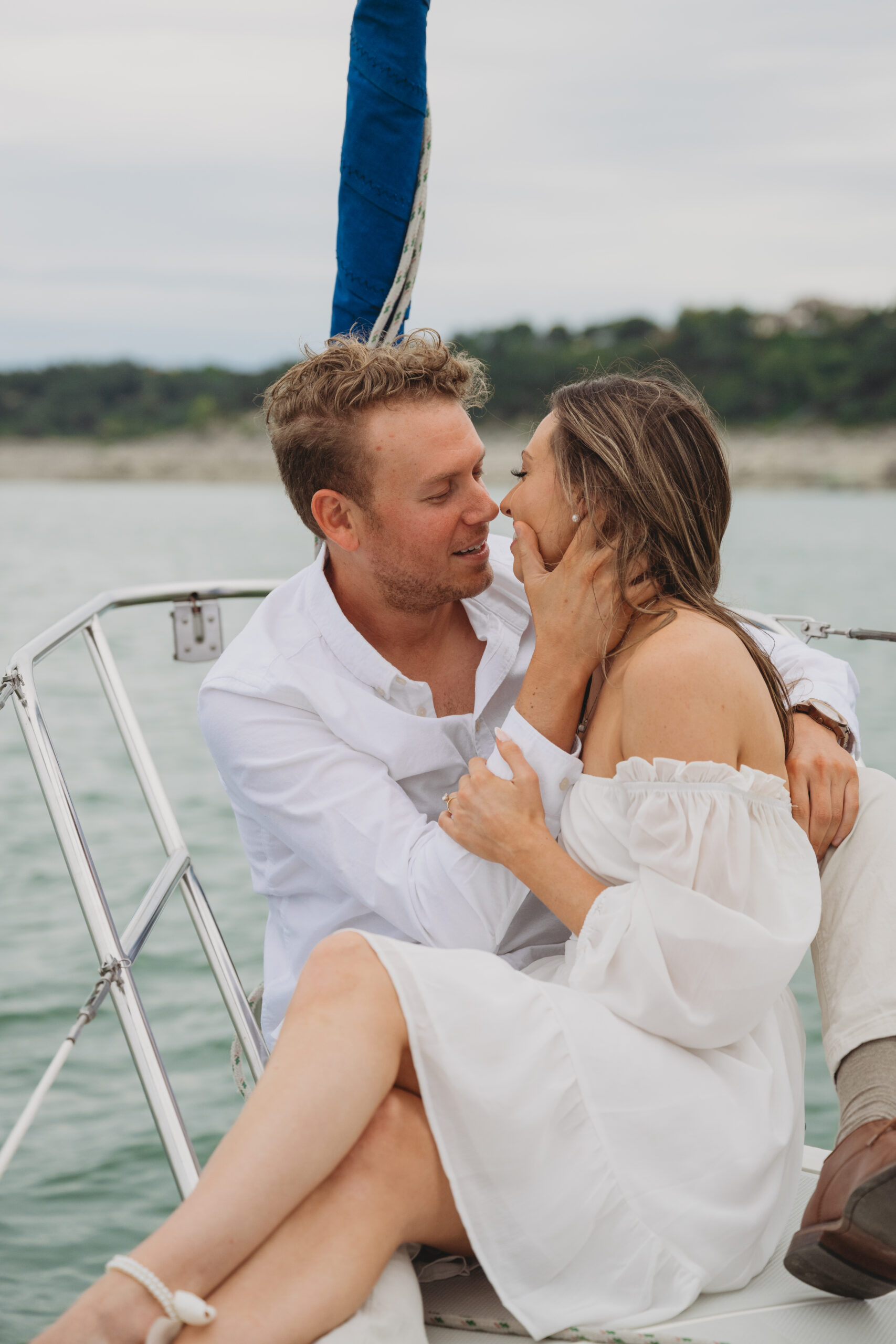 couple shares a romantic moment during sailboat engagement session