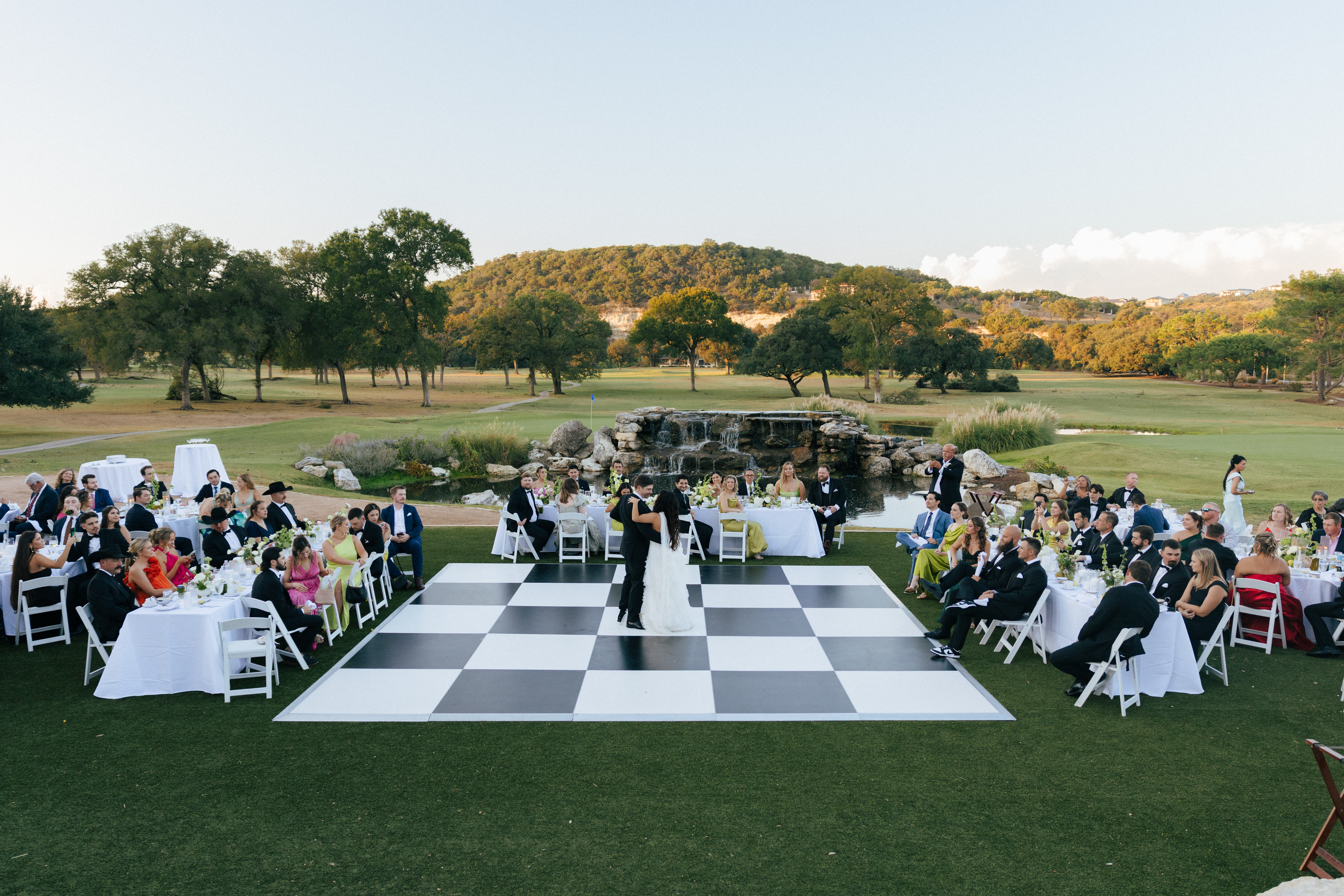 classic blank and white dance floor install on golf course wedding venue under sunset